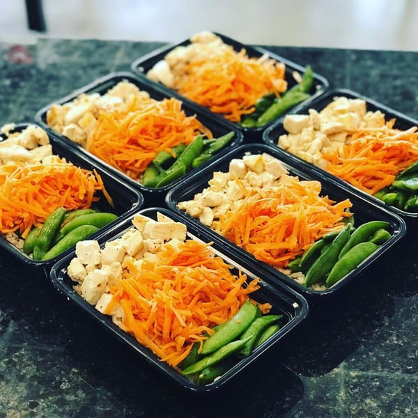 Six healthy Fit Factory Grill meal prep containers with chicken, shredded carrots, and snap peas.