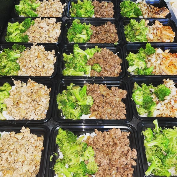 Rows of healthy meal prep containers with broccoli, ground meat, and chicken.