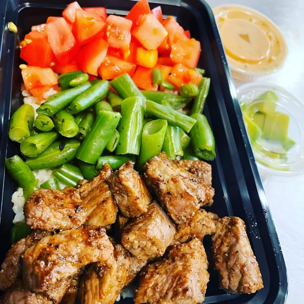 Fit Factory Grill's healthy meal with steak, green beans, and diced tomatoes in a black container.