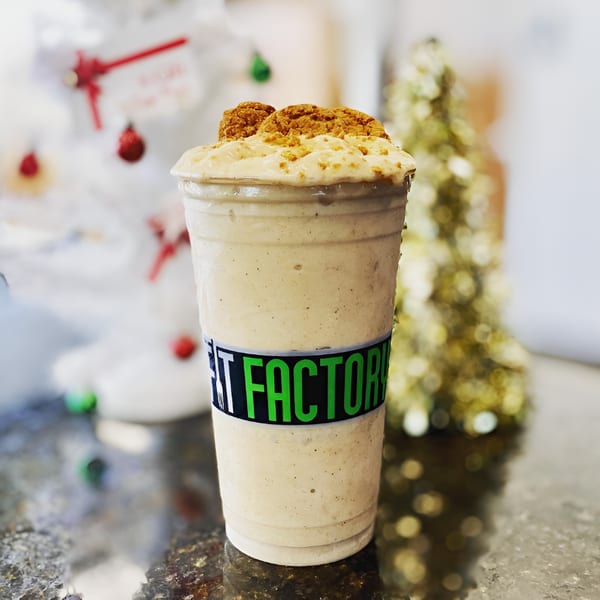 Fit Factory Grill smoothie with cookie crumbles, set against a festive, blurred holiday background.