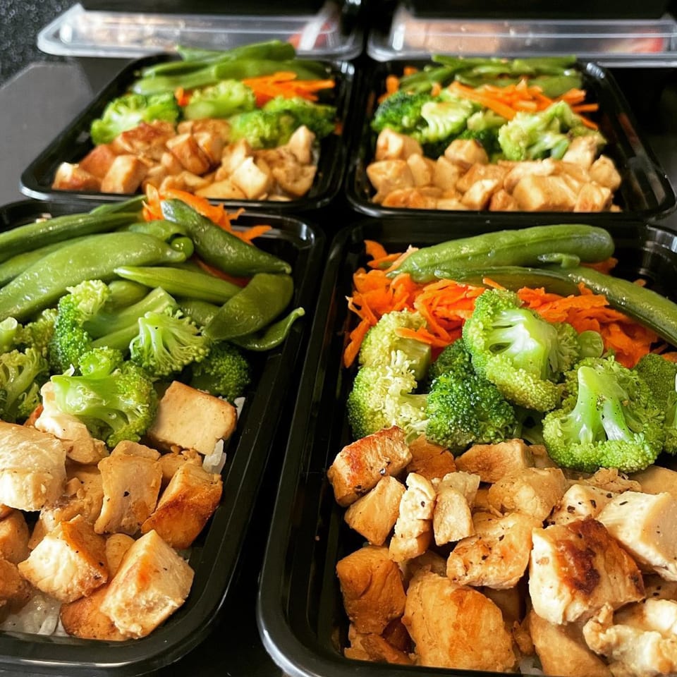 Four healthy Fit Factory Grill meal prep containers with chicken, broccoli, snap peas, and carrots.